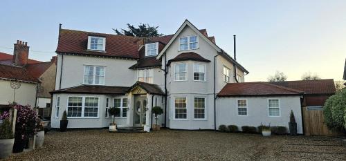 a large white house with a driveway at Burlington Berties in Sheringham