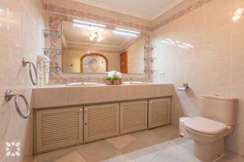 Un baño con lavabo, inodoro y espejo. en Villa Gaviota by Abahana Villas, en Cap Blanc