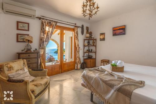 Un dormitorio con una cama y una silla y una ventana. en Villa Gaviota by Abahana Villas, en Cap Blanc