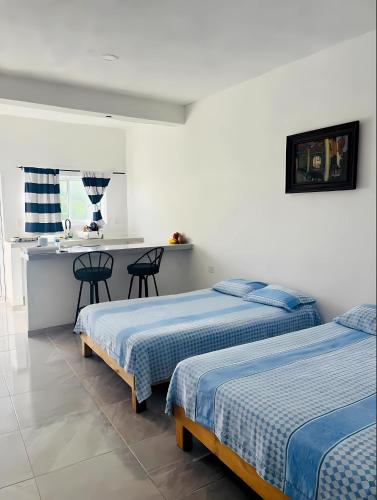 a bedroom with two beds and a kitchen with a counter at El Amanecer de Chiltepec in Chiltepec