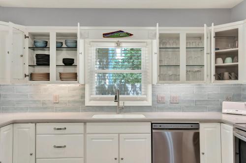 a kitchen with white cabinets and a sink and a window at The Oar House in Tybee Island
