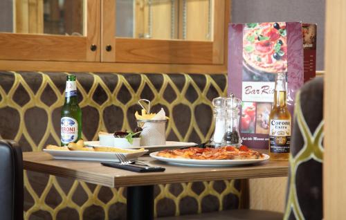 a table with two plates of food and bottles of beer at Columba Hotel in Oban