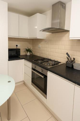 a kitchen with white cabinets and a stove top oven at East London Suites in London