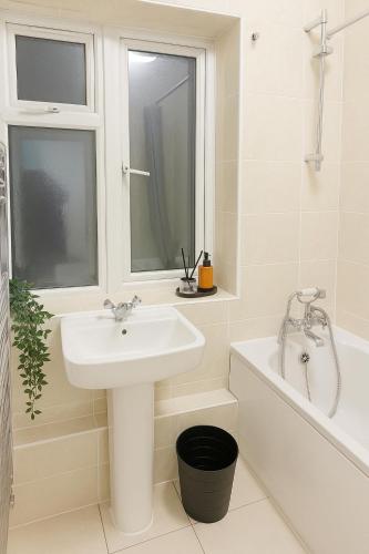 a white bathroom with a sink and a bath tub at East London Suites in London