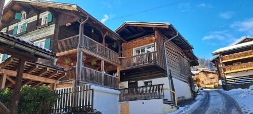 a wooden house with a balcony on a street at Gadänäscht in Jenaz