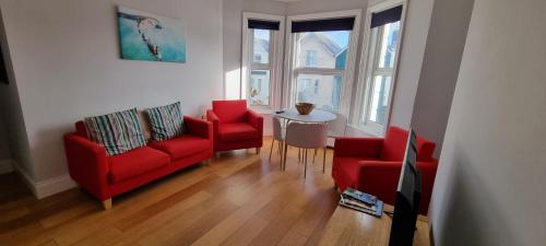 a living room with two red chairs and a table at Sandown Seaside apartment First Floor Kasala in Sandown