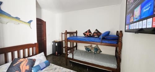a room with two bunk beds and a tv at Suíte Trilha do Sol 2 in Arraial do Cabo