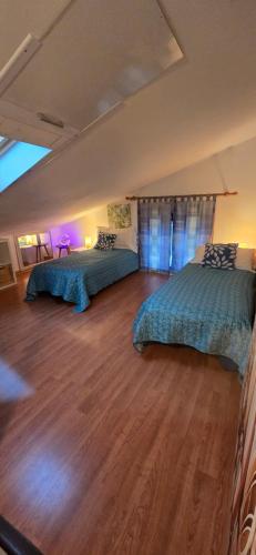 two beds in a large room with wooden floors at Appartamento Tortuga in Lignano Sabbiadoro