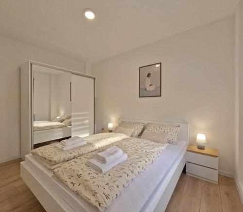 a bedroom with a large white bed and a mirror at Apartman Anita in Kupres