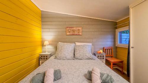 ein Schlafzimmer mit einem Bett mit gelben Wänden in der Unterkunft Petit Chalet idéal à la campagne avec wifi et parking in Auguaise