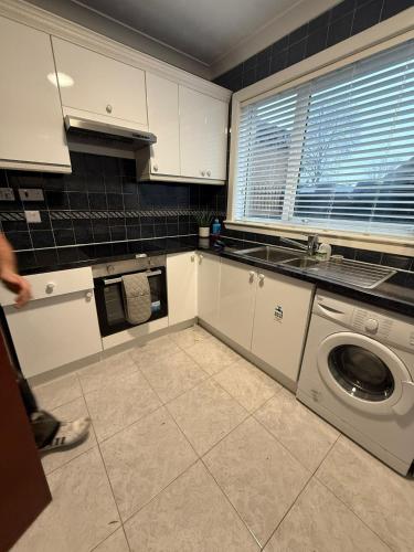 a kitchen with a washer and a washing machine at Vacant Nests Ivy Cottage 3BR Wi-Fi in Banton
