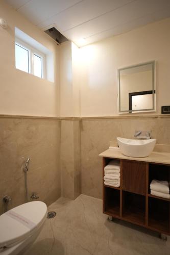 a bathroom with a sink and a toilet and a mirror at Rambagh Resort by Stotrak, Gwalior in Gwalior