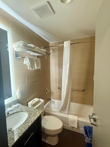 a bathroom with a toilet and a tub and a sink at Days Inn by Wyndham Brooklyn Borough Park in Brooklyn