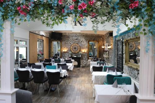 um restaurante com mesas brancas, cadeiras e flores em Townsend House Guest House em Birr