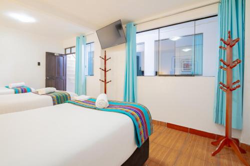 zwei Betten in einem Zimmer mit blauen Vorhängen in der Unterkunft Inkary Hotel Machupicchu in Machu Picchu