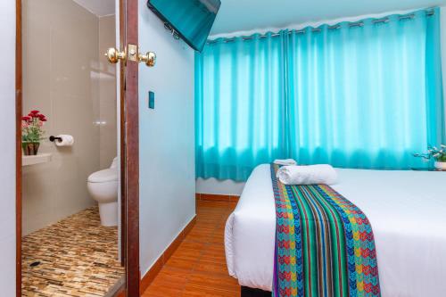 Schlafzimmer mit einem Bett, einem WC und blauen Vorhängen in der Unterkunft Inkary Hotel Machupicchu in Machu Picchu