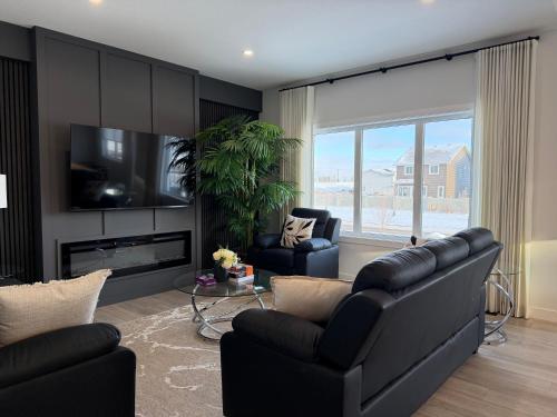 a living room with black furniture and a large window at Cozy Heaven in Saskatoon