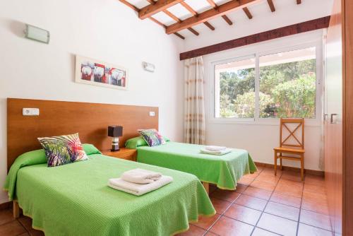 Dos camas verdes en una habitación con ventana. en Villa Casa de Olives, en Cala Galdana