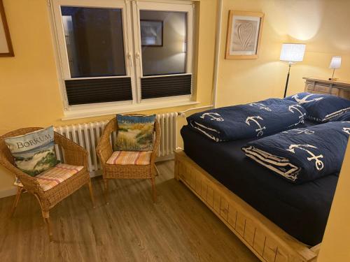 博尔库姆Ferienhaus Fehlhaber的一间卧室，有一张床、两把椅子和一扇窗户