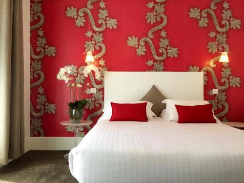 une chambre avec des murs rouges et un lit avec des oreillers rouges dans l'établissement Hotel Villa Rose, à Nice