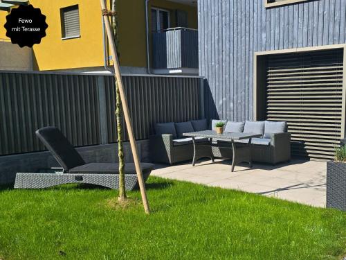 a patio with chairs and a table in the grass at Ferienhausträume - ebenerdiges Bodensee Apartment mit Garten und großer Terrasse mit Grill in Kreuzlingen