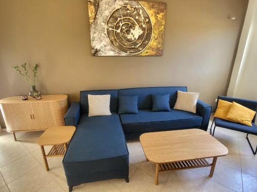 een woonkamer met een blauwe bank en tafels bij Aegean Helios Houses in Gennadi