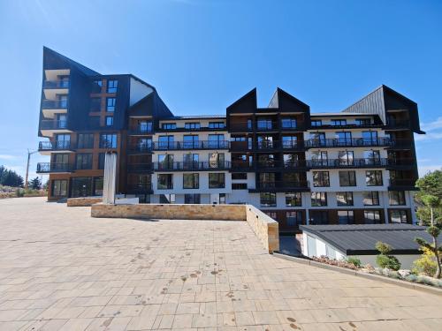 a large black and white building with a brick courtyard at Harmony, Residence Hill A85 in Kopaonik