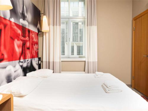 um quarto com uma cama e uma parede vermelha em Ibis Riga Centre em Riga