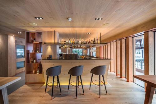 a kitchen with a bar with three stools at Hotel Garni Dolomieu in Selva di Val Gardena