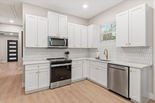 een keuken met witte kasten en een kookplaat oven bij Modern NB Getaway with Pool in New Braunfels