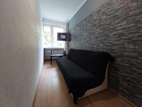 a living room with a couch and a brick wall at 2051 Zwycięstwa 23 - Tanie Pokoje - samodzielne zameldowanie - self check in in Poznań