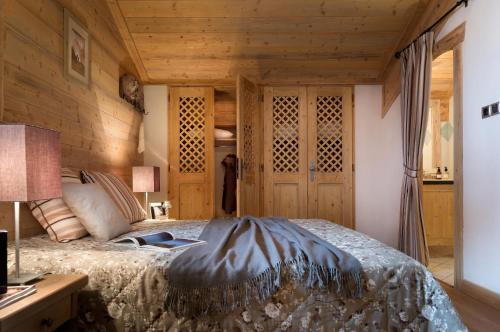a bedroom with a bed and a wooden wall at CGH Résidences & Spas Les Clarines in Les Menuires