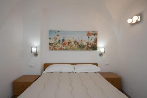 ein Schlafzimmer mit einem Bett und einem Gemälde an der Wand in der Unterkunft Dalia's Home Garden and Private Parking in Calice Ligure