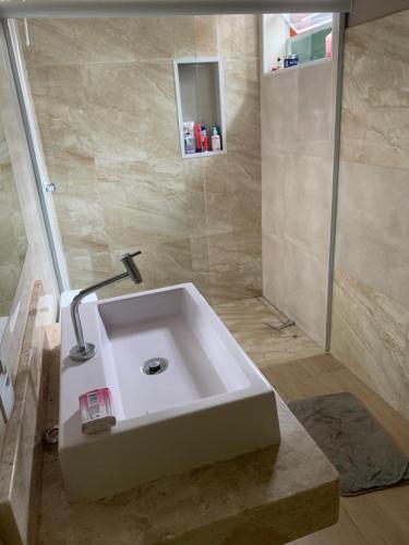 a bathroom with a white sink and a shower at Recanto Pedrita in Pedreira