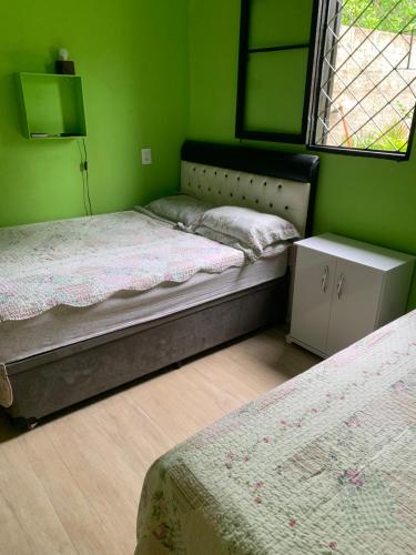 due letti in una stanza con pareti verdi di Recanto Pedrita a Pedreira