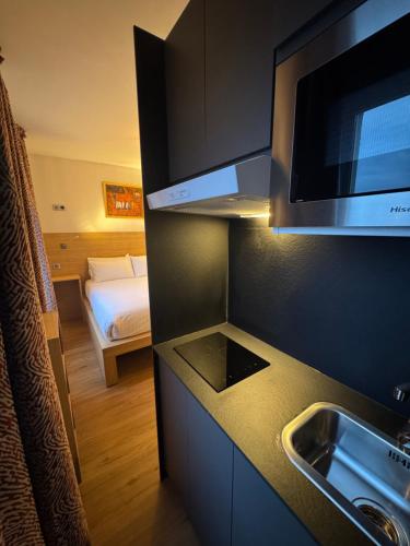 a kitchen with a sink and a microwave and a bedroom at Hôtel Montmartre - Nouvellement Rénové in Paris