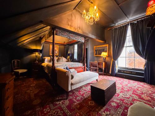 a bedroom with a canopy bed with a chair and a table at Guy Fawkes Inn in York