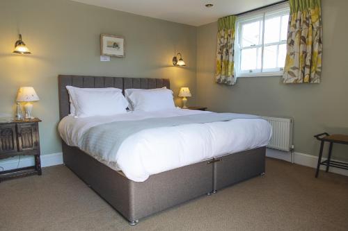 a bedroom with a large bed with white sheets and a window at Blue Ball Inn in Sidmouth