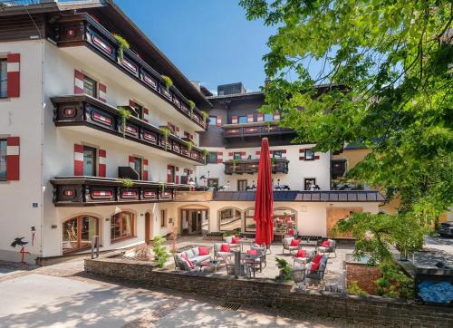 GRETI - wie dahoam, nur feiner - Alpine Boutique Hotel mit Alpentherme Eintritt, reichhaltigem Frühstück, Sauna في باد هوفغاستين: فندق به فناء مع مظلات وكراسي حمراء