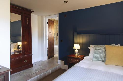 a bedroom with a large bed with a blue wall at The Blue Ball Inn in Sidmouth