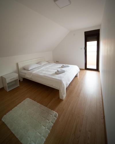 a white bedroom with a bed and a wooden floor at Ilic House in Belgrade