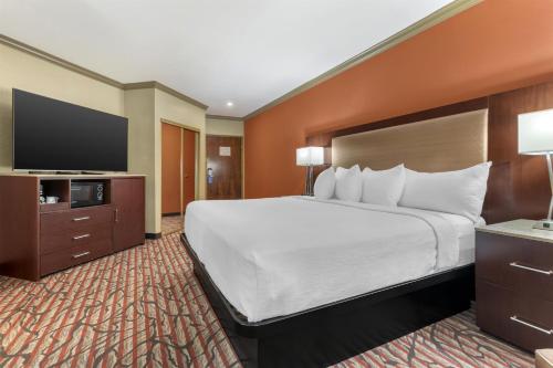 a hotel room with a large bed and a flat screen tv at Best Western Plus Brookside Inn in Milpitas