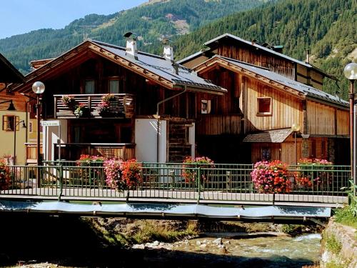 a wooden house with flowers in front of it at Appartamento Rita in Pozza di Fassa