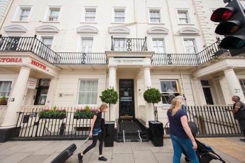 two women walking in front of a building with luggage at St George's Inn Victoria in London