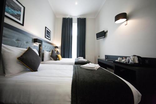a hotel room with two beds and a window at St George's Inn Victoria in London