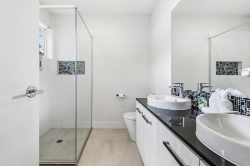 Modern Family Home in Peaceful Pallara 4BR Comfort في Algester: حمام أبيض مع مغسلتين ودش