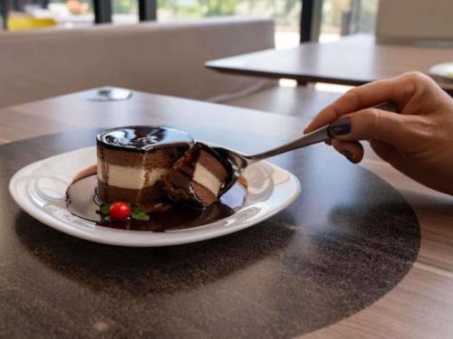 a person eating a piece of chocolate cake on a plate at ibis Styles Taubate in Taubaté