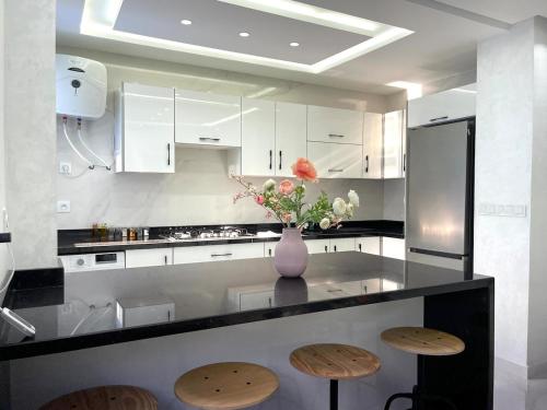 una cocina con encimera con taburetes y un jarrón con flores en Luxurious condo with patio and terrace, en Alhucemas