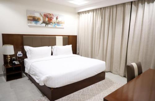 Un dormitorio con una gran cama blanca en una habitación. en إس بي واي للشقق المخدومة - SBY Serviced Apartments, en Buraidah