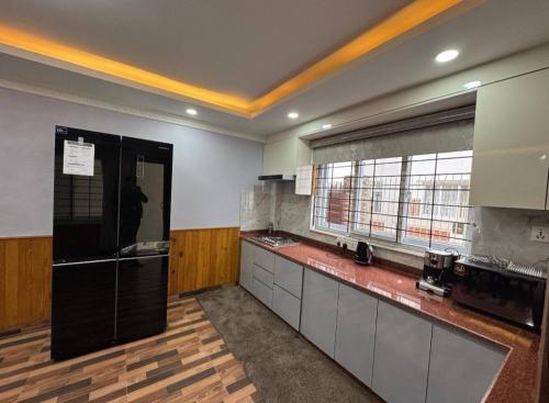 Una cocina grande con un refrigerador negro y una ventana. en MeroBasai - Budhanilkantha Residence, en Burhānilkantha